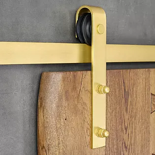 Sistema de porta corredissa fet dacer en color daurat, per a portes duna sola fulla de fins a 100 kg, muntat a la paret