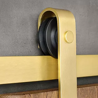 Sistema de porta corredissa fet dacer en color daurat, per a portes duna sola fulla de fins a 100 kg, muntat a la paret
